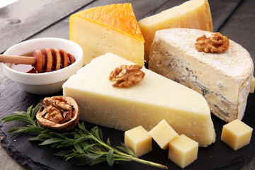 Different types of cheeses on board with walnut and grapes