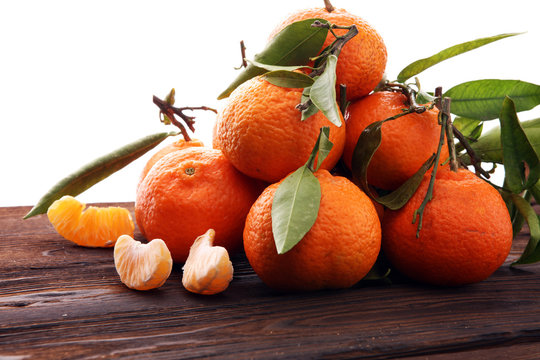 Tangerines with leaves on wooden background. Mandarins Rustic style.