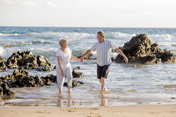 lovely senior mature couple on their 60s or 70s retired walking happy and relaxed on beach sea shore in romantic aging together