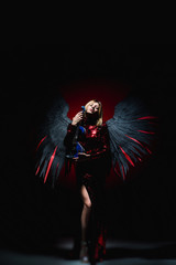 Female with big angel wings on black background.