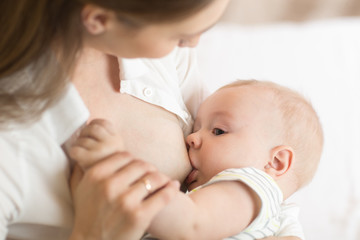 Obraz na płótnie Canvas Young mother holding her newborn child. Mom nursing baby. Pretty woman breastfeeding kid.