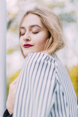 portrait of a luxurious, beautiful, young girl. Dressed in stylish clothes, walking in an autumn park. Bright lipstick on the lips.