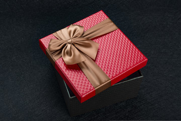 red gift box with brown bow on dark background