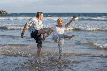 lovely senior mature couple on their 60s or 70s retired walking happy and relaxed on beach sea...