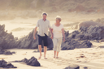 lovely senior mature couple on their 60s or 70s retired walking happy and relaxed on beach sea shore in romantic aging together