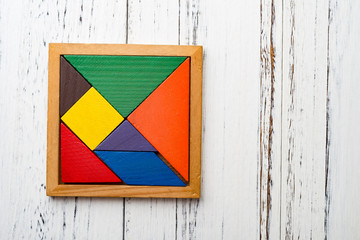 set of wooden tangram on white wood background