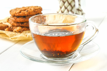 Homemade oatmeal cookies and tea on a wooden white table.
