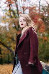 portrait of a luxurious, beautiful, young girl. Dressed in stylish clothes, walking in an autumn park. Bright lipstick on the lips.