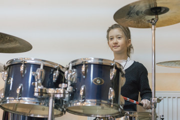 Happy girl in music therapy by playing drum kit on music room