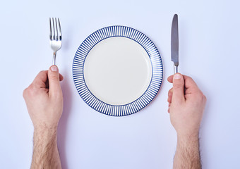 Man's hands with cutlery and empty plate isolated on white