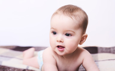 Portrait of a smiling crawling baby on the bed in her room. Space for text