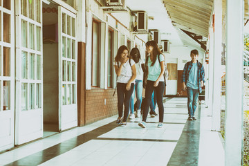 Group of mixed races teenagers group walking and smiling along school hallway