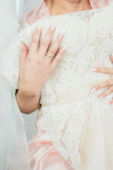 close-up of the hands of the bride with a wedding ring and a beautiful wedding dress that the bride presses to herself