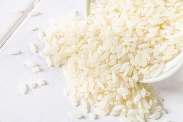 Grains of raw white rice on a white wooden table of boards. Ingredients for cooking.