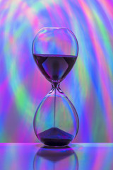 Hourglass on a multi-colored background. Close-up. - 185015032