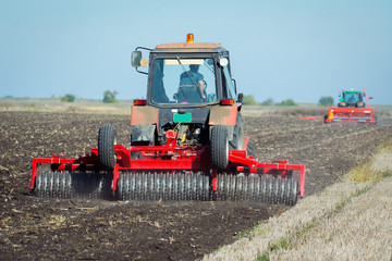Fototapeta premium Tractor with a roller on the field at spring