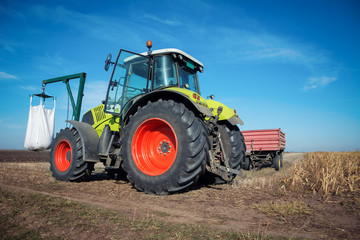 Modern tractor working in a field on a sunny day. Agricultural machinery during planting.