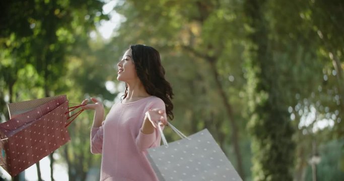 happy beautiful Asian girl with shopping bags having fun walking down the street, slow motion