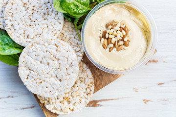 Healthy Snack from Rice Cakes with Hummus, Spinach and Tomatoes