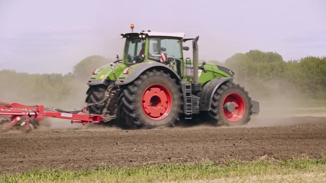 Farming tractor and trailer seeder making scattering arable field. Process sowing plowed field. Agricultural equipment