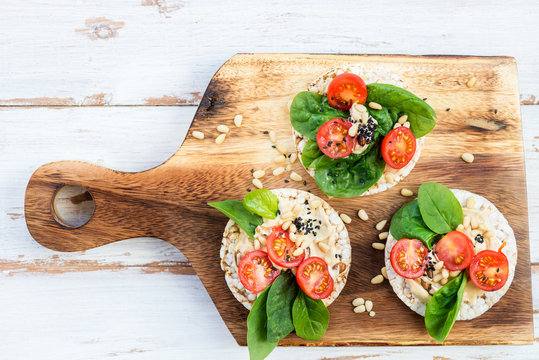 Healthy Snack from Rice Cakes with Hummus, Spinach and Tomatoes