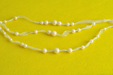 White beads displayed on a white ribbon isolated on a yellow background