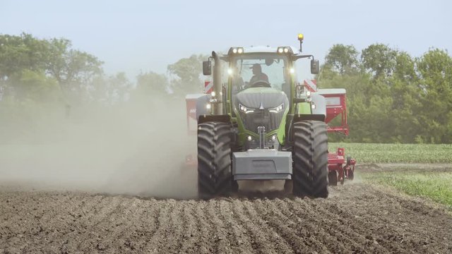 Farm tractor moving on agricultural field. Agricultural tractor working in field. Process plowing and sowing field. Agricultural equipment