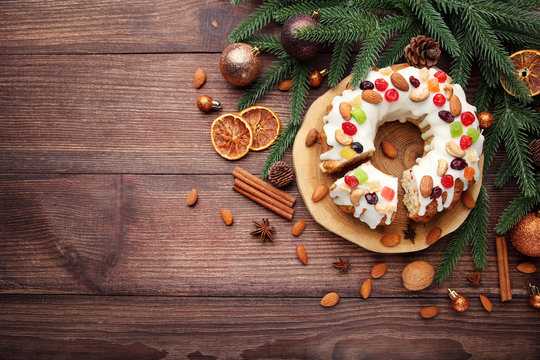 Bundt cake with fir-tree branches and christmas baubles on wooden table