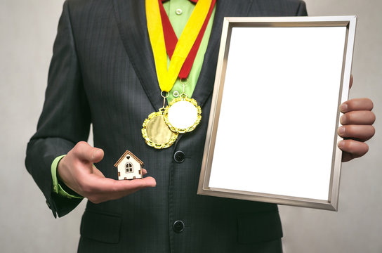 Best real estate agent certificate mock up. Insurance agent diploma. Realtor man holds in one hand empty blank photo frame with copy space and a toy house in another hand.