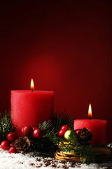 Christmas candle with fir-tree branches and berries on red background