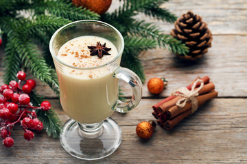 Eggnog in glass with star anise and cinamon on wooden table