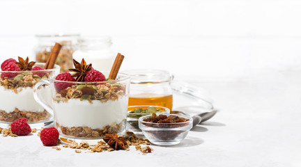 spicy dessert with sweet granola, raspberries and yogurt in the glass on white background