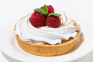 sweet tartlet with meringue and raspberry on white plate