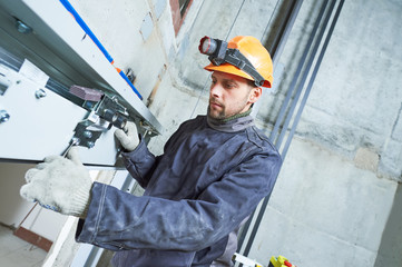 machinist with spanner adjusting lift mechanism in elevator shaft © Kadmy
