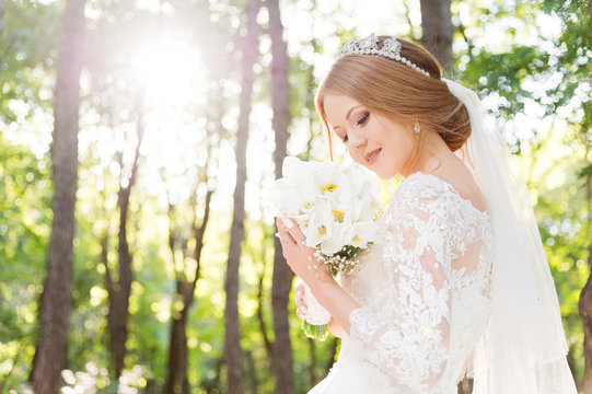 Portrait of a beautiful bride in a white dress and a bouquet of flowers in her hands
