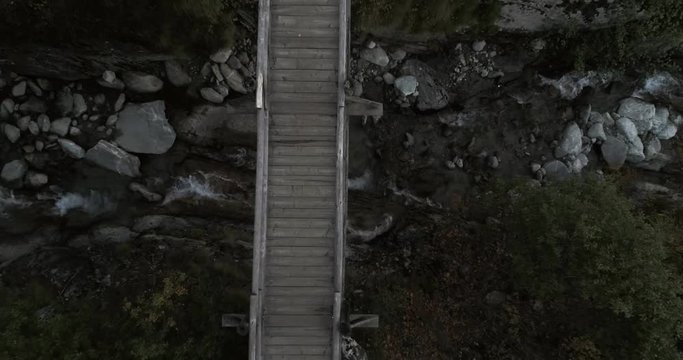 Wooden bridge, Cinema 4k aerial rising view over a forest bridge and a river, in the mountains, on a sunny autumn day, near blatten, in Valais, in the alps of Switzerland