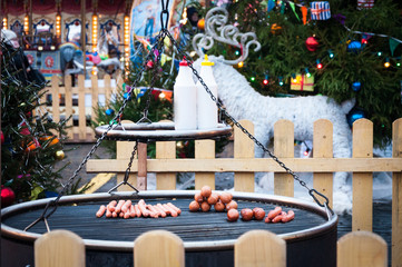 Christmas Market in Red Square, Moscow. Preparation of sausages and sausages on a grill for hot dogs