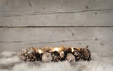classic golden Christmas tealight holder with burning candles, on sheepskin and weathered wooden background