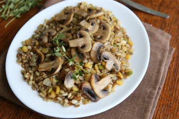 Cooked mixed  grains cereal with champignon mushroom for healthy meal. Various cereals (pearl barley, oats, rye, peas, lentil) porridge in plate.