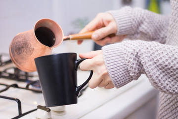 Fototapeta na wymiar Woman making coffee in the kitchen wearing a knitted jersey
