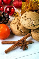 Many New Year's, Christmas attributes. A hill of cookies and spices. Red balls and gold gifts for a Christmas tree in the background. Cones and mandarins for composition.