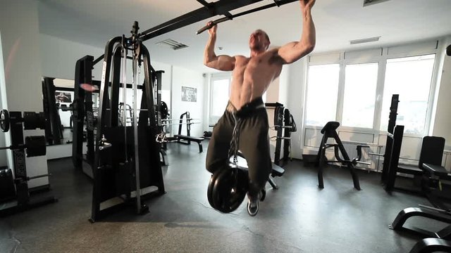 Athlete does pull-up on the crossbar, on his belt an additional load.