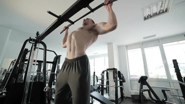 Athlete does pull-up on the crossbar, he trains in the gym.