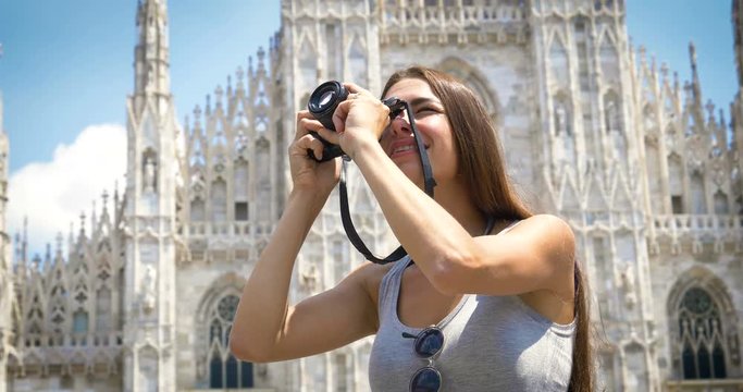 Beautiful young tourist girl, woman in Milan, holding a photo camera, taking pictures, happy smiling, background Milan gallery. Concept tourism, love travel, communication, freedom, love life shopping
