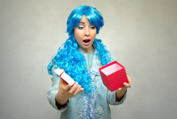 Surprised snow maiden girl with blue long hair with Chrismas present box gift in hands isolated on gray background.