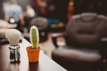 brush for shaving beard along with bowl, blurred background of hair salon for men, barber shop