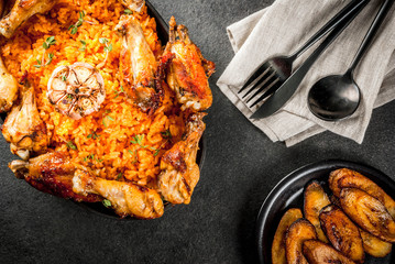 West African national cuisine. Jollof rice with grilled chicken wings and fried bananas plantains.On gray stone table. Copy space  top  view © ricka_kinamoto