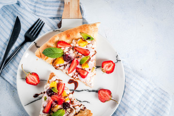 Summer snacks. Food for party. Fruit pizza with cream, currants, yogurt, strawberries, mango, peaches, bananas, blackberries, chocolate, walnuts, mint. On light blue table. Copy space top view