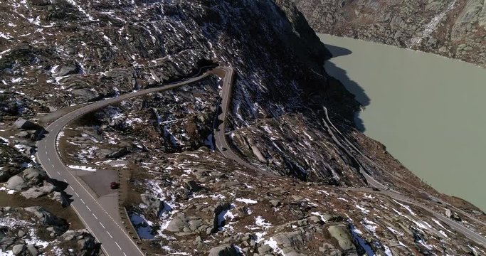 Car on a mountain road, Cinema 4k aerial backward view of cars on a snowy alp road, on the top of grimsel pass, on a sunny autumn day, in bern and Valais, alps of Switzerland