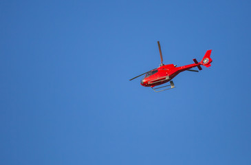 Fototapeta na wymiar Hélicoptère rouge en vol sur un beau ciel bleu